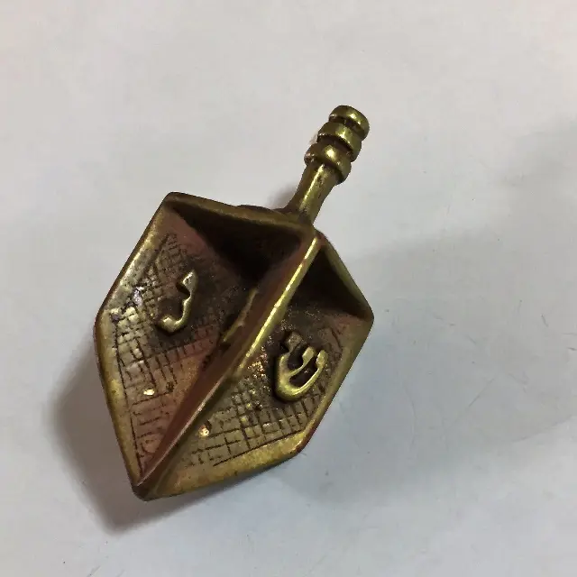 Brass winged Dreidel with the inscription "נ,ג,ה,ש."