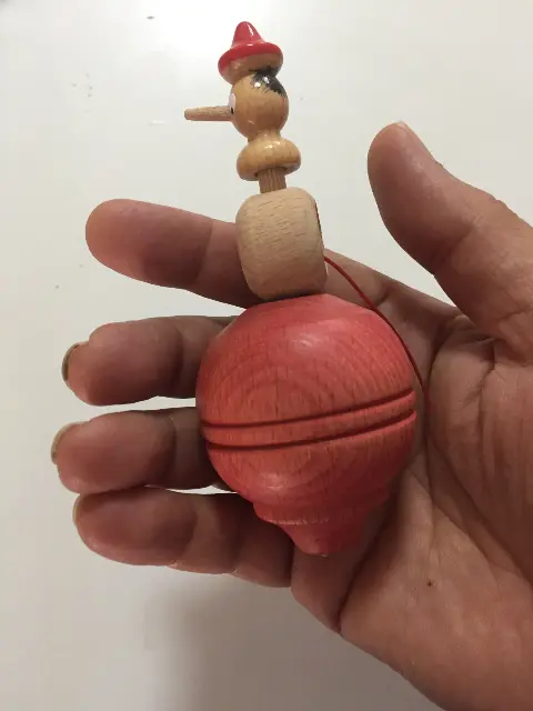 Pinocchio spinning top with long nose and launcher ring with string